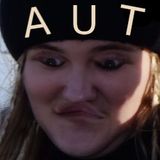 En bild på Tua med en svart basker och uppochnedvänd mun och ögon. AUT är bokstaverat på hennes basker.